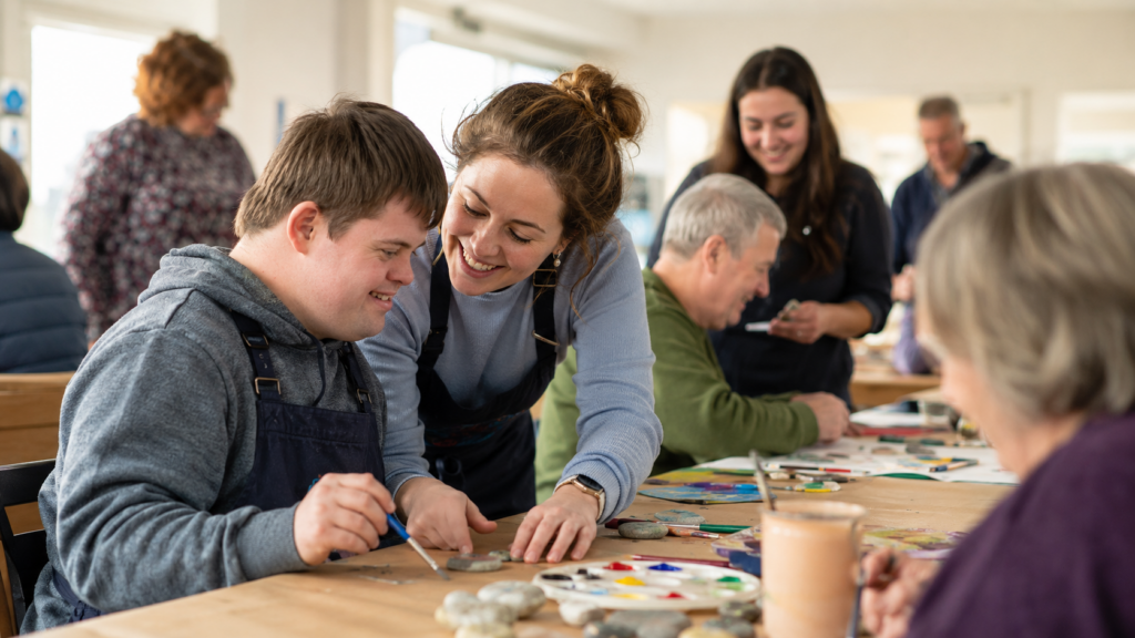 Volunteer supporting an adult with an intellectual disability during an inclusive community art workshop in Ireland
